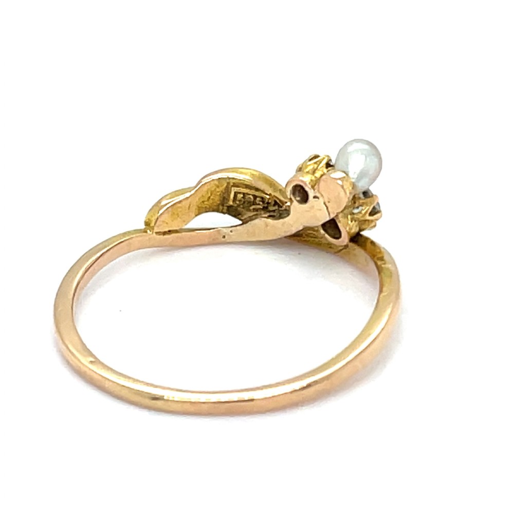 An Art Nouveau gold ring featuring a single white pearl paired with two diamonds on a sinuous flowing band. View II