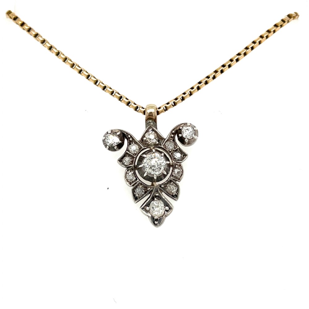 A Victorian silver-topped gold pendant set with diamonds in a scrollwork arrangement, suspended from a gold box chain.