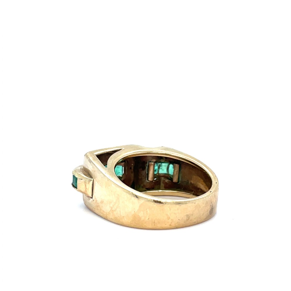 An Art Deco yellow gold tank ring featuring a row of channel-set green rectangular emeralds across a bold architectural setting. View III