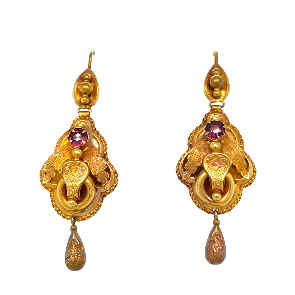 A pair of Victorian yellow gold drop earrings decorated with foliate metalwork, engraved details, and round bezel-set red garnet gemstones. View II