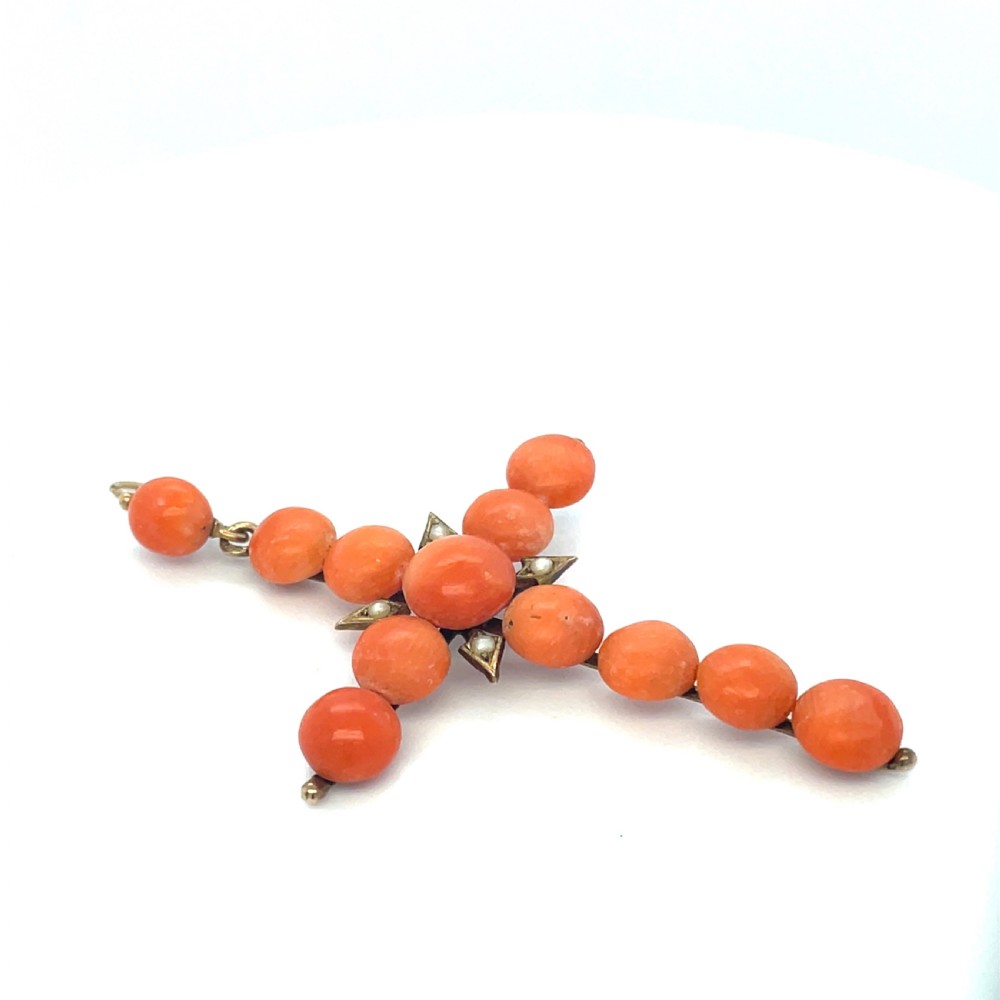 An antique Georgian cross pendant crafted from spherical orange coral beads accented with small seed pearls on a gold mounting.