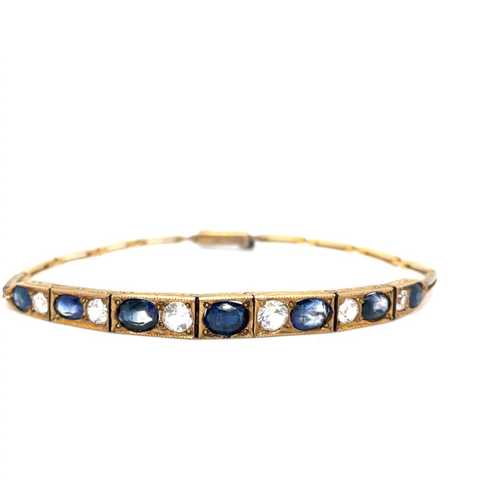 An Edwardian 9ct gold link bracelet featuring alternating set blue sapphires and clear round gemstones in articulated rectangular panels. View II