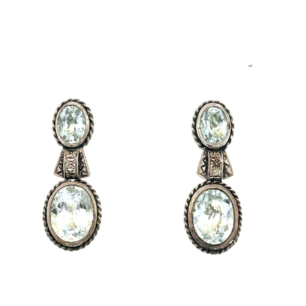 A pair of late 19th-century silver drop earrings set with two oval-cut pale blue aquamarines enclosed in rope-twist borders.