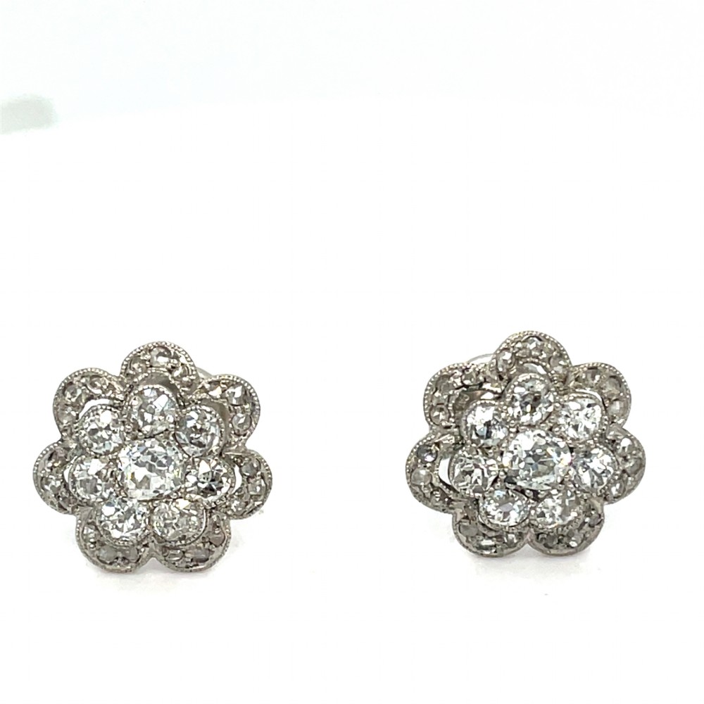 A pair of floral-shaped stud earrings set with central old European cut diamonds surrounded by millegrain-bordered diamond petals.