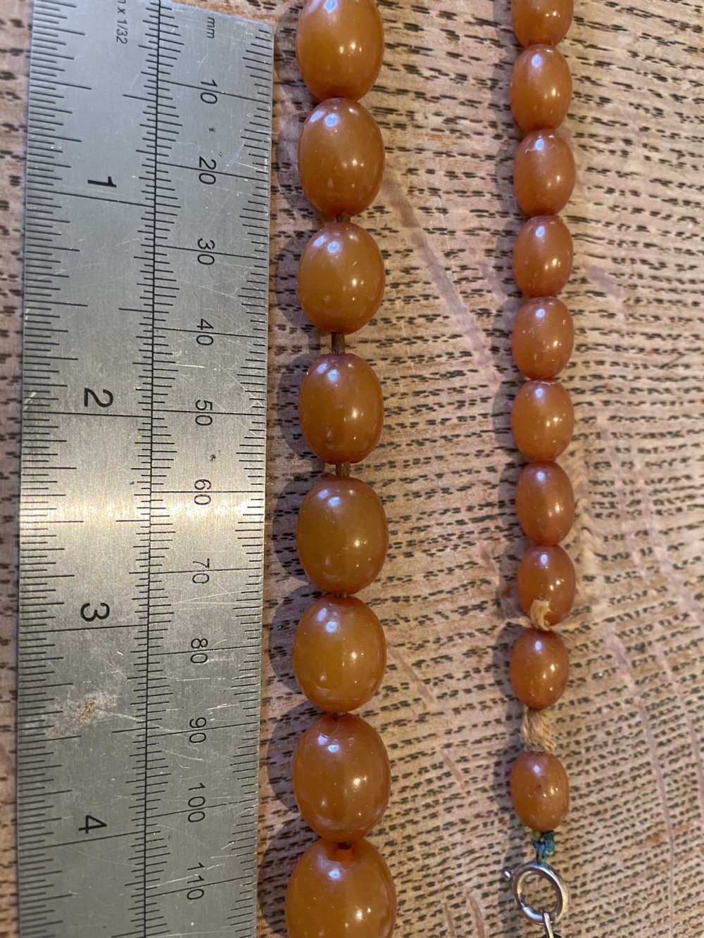 A strand of polished, oval-shaped natural Baltic amber beads in warm honey tones with a metal clasp. View III