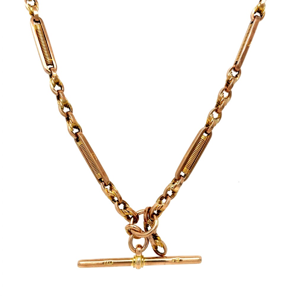A Victorian 9ct rose gold watch chain featuring fancy bar links, twisted loop connectors, and a central hallmarked T-bar.