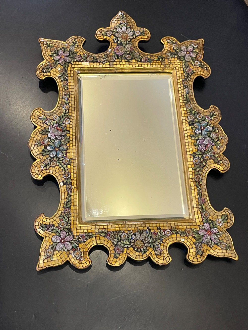 A 19th-century Italian micro mosaic wall mirror featuring a shaped gold tesserae frame decorated with colourful mosaic flowers around a rectangular mirror glass.
