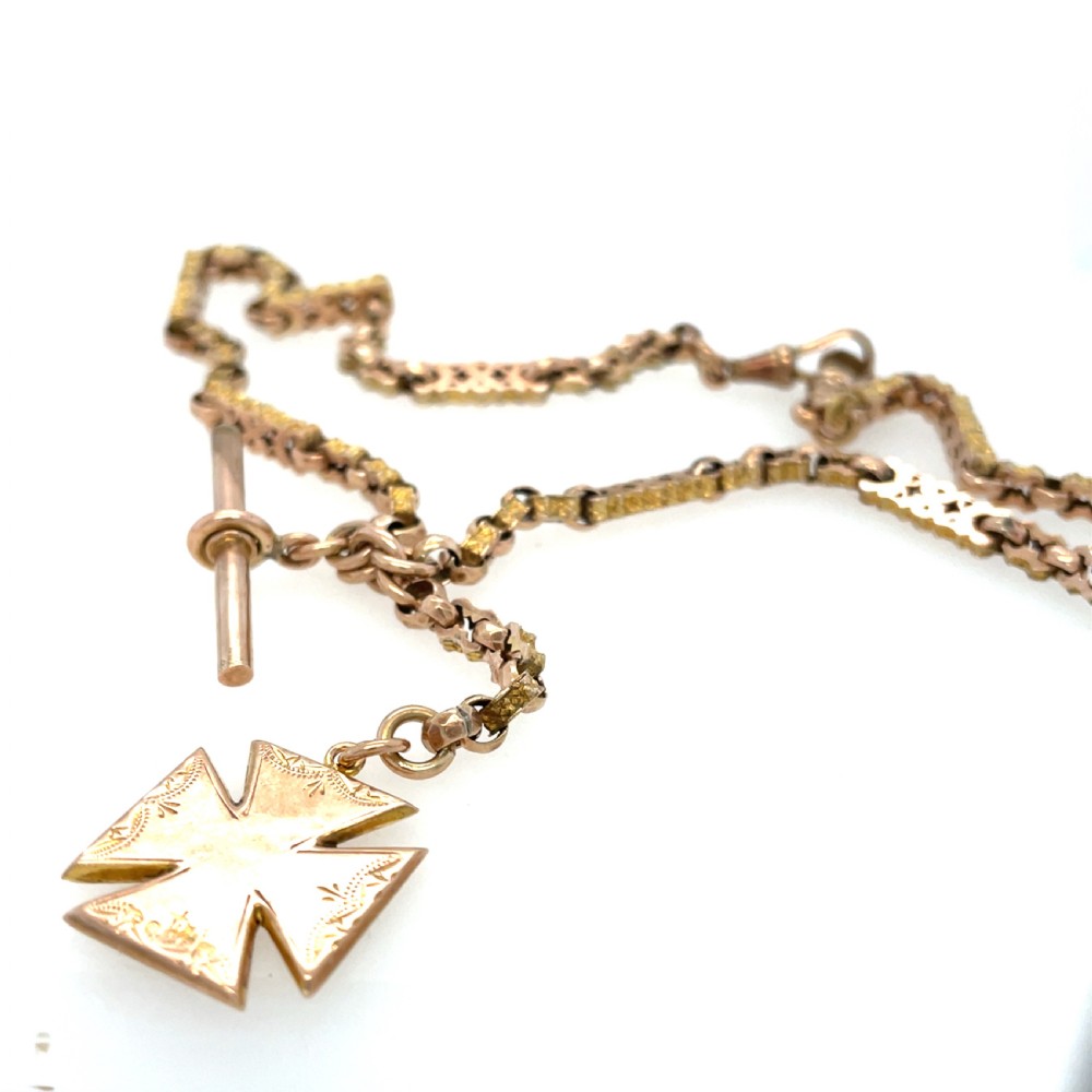 An antique 9ct rose gold Albert chain featuring textured links, a T-bar attachment, and an engraved cross-shaped fob pendant.