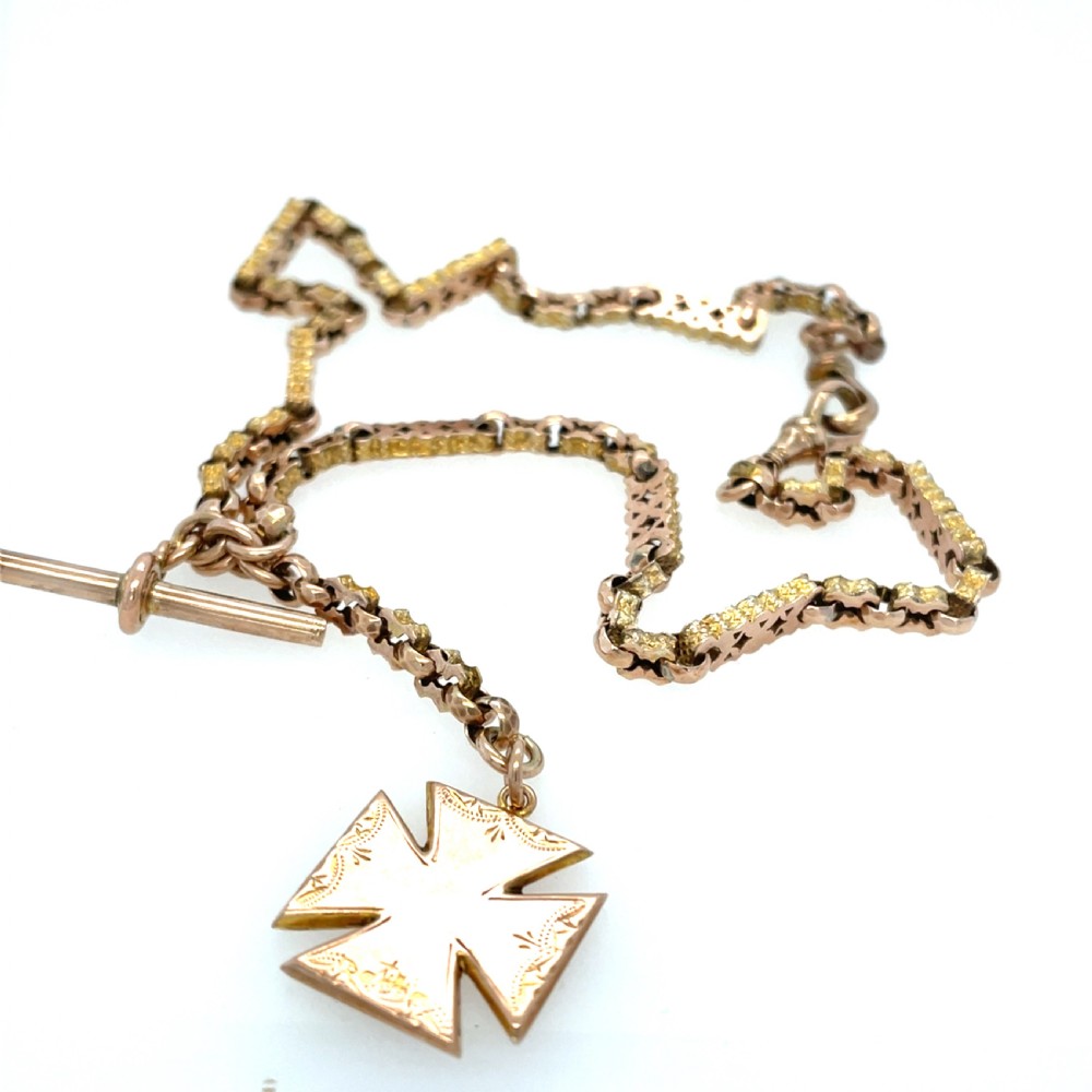 An antique 9ct rose gold Albert chain featuring textured links, a T-bar attachment, and an engraved cross-shaped fob pendant. View II