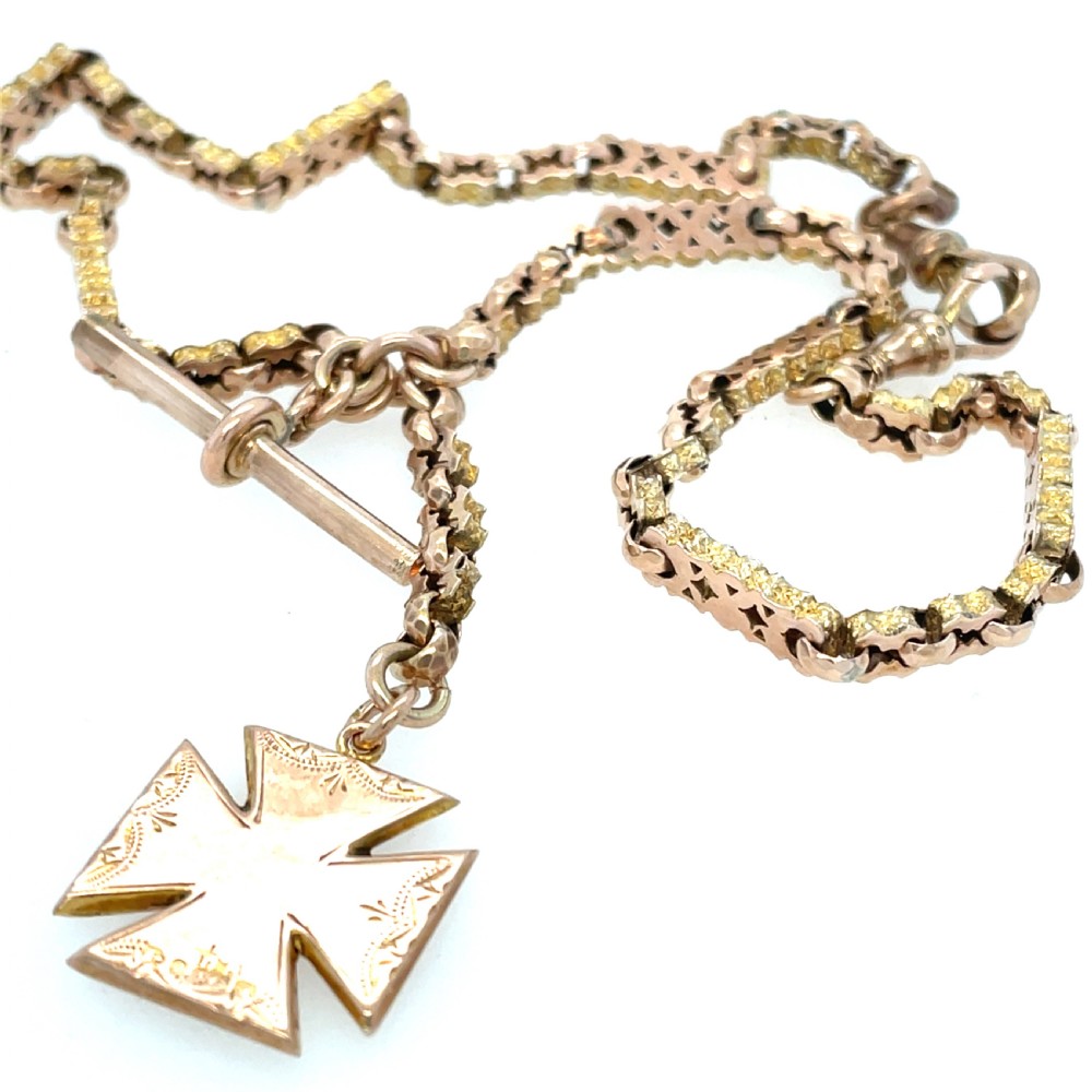 An antique 9ct rose gold Albert chain featuring textured links, a T-bar attachment, and an engraved cross-shaped fob pendant. View III