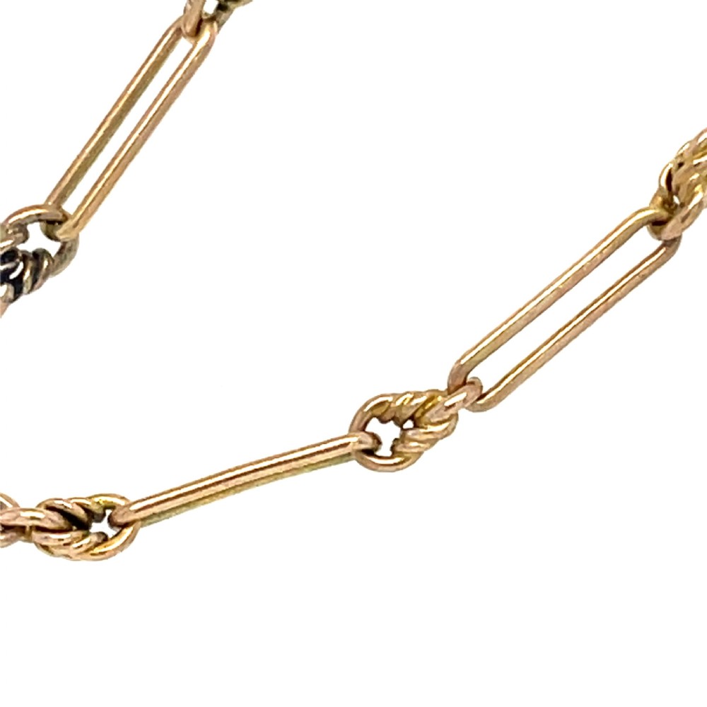 An Edwardian 9ct yellow gold longuard chain featuring elongated links, twisted wire connectors, green gemstone beads, and a circular bolt ring fastener. View II