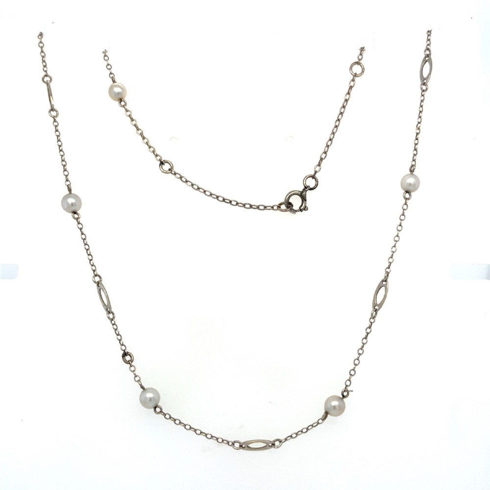 An antique 9ct white gold necklace featuring saltwater pearls spaced along a fine trace chain with elongated oval links.