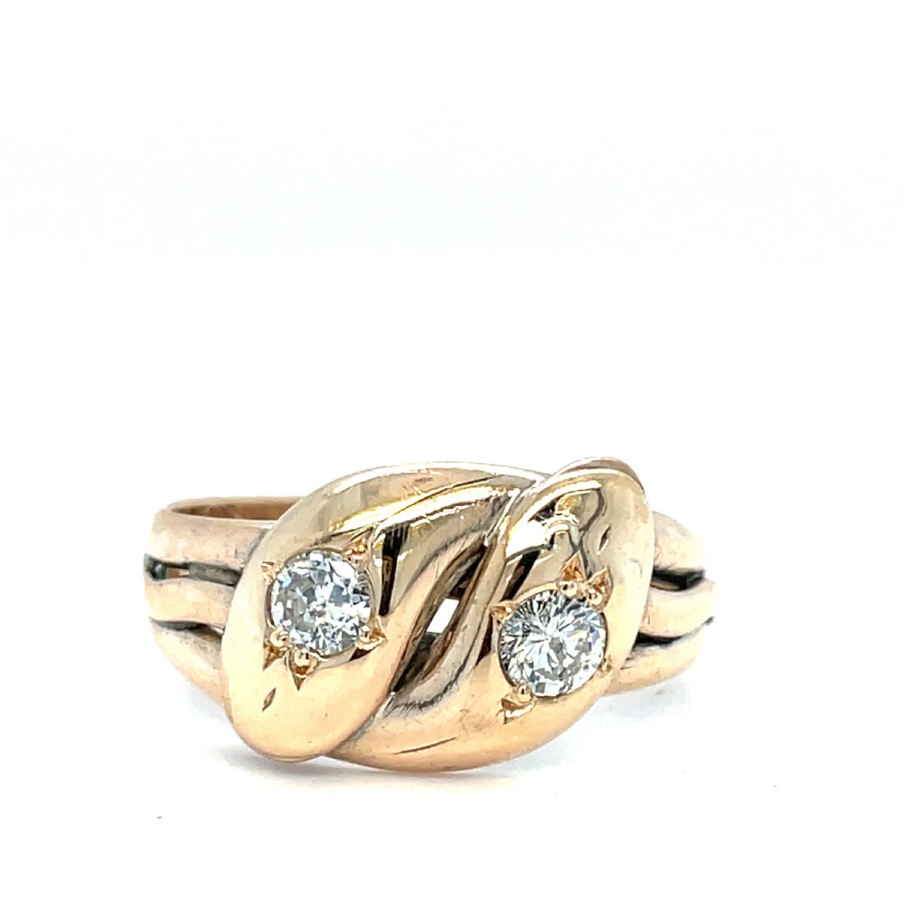 An antique yellow gold ring crafted with two entwined snake heads, each set with a round cut diamond.