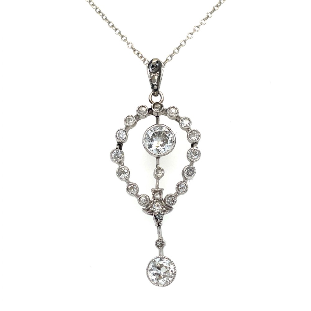 An Edwardian platinum and diamond drop pendant featuring an openwork oval bezel set with old-cut diamonds and an articulated center stone.