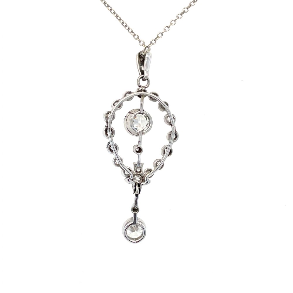 An Edwardian platinum and diamond drop pendant featuring an openwork oval bezel set with old-cut diamonds and an articulated center stone. View III