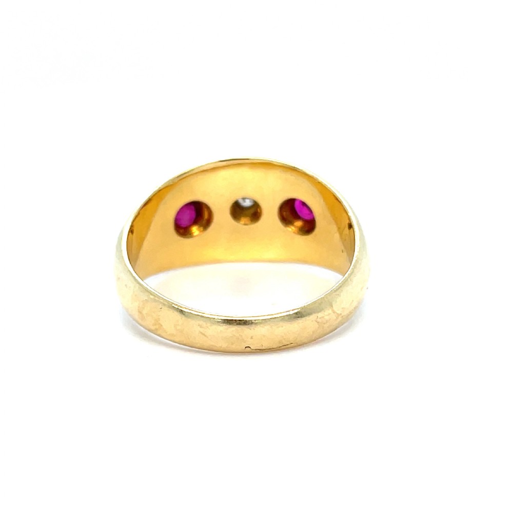 An Edwardian 18ct yellow gold band ring set with a central diamond flanked by two red rubies within starburst engravings. View II