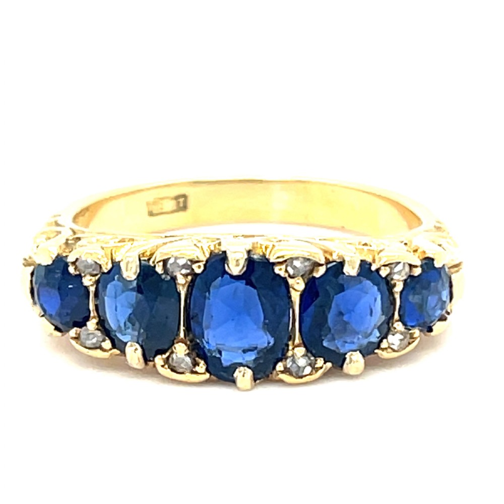 A Victorian 18ct yellow gold boat ring set with five graduated oval blue sapphires and small diamond accents. View II