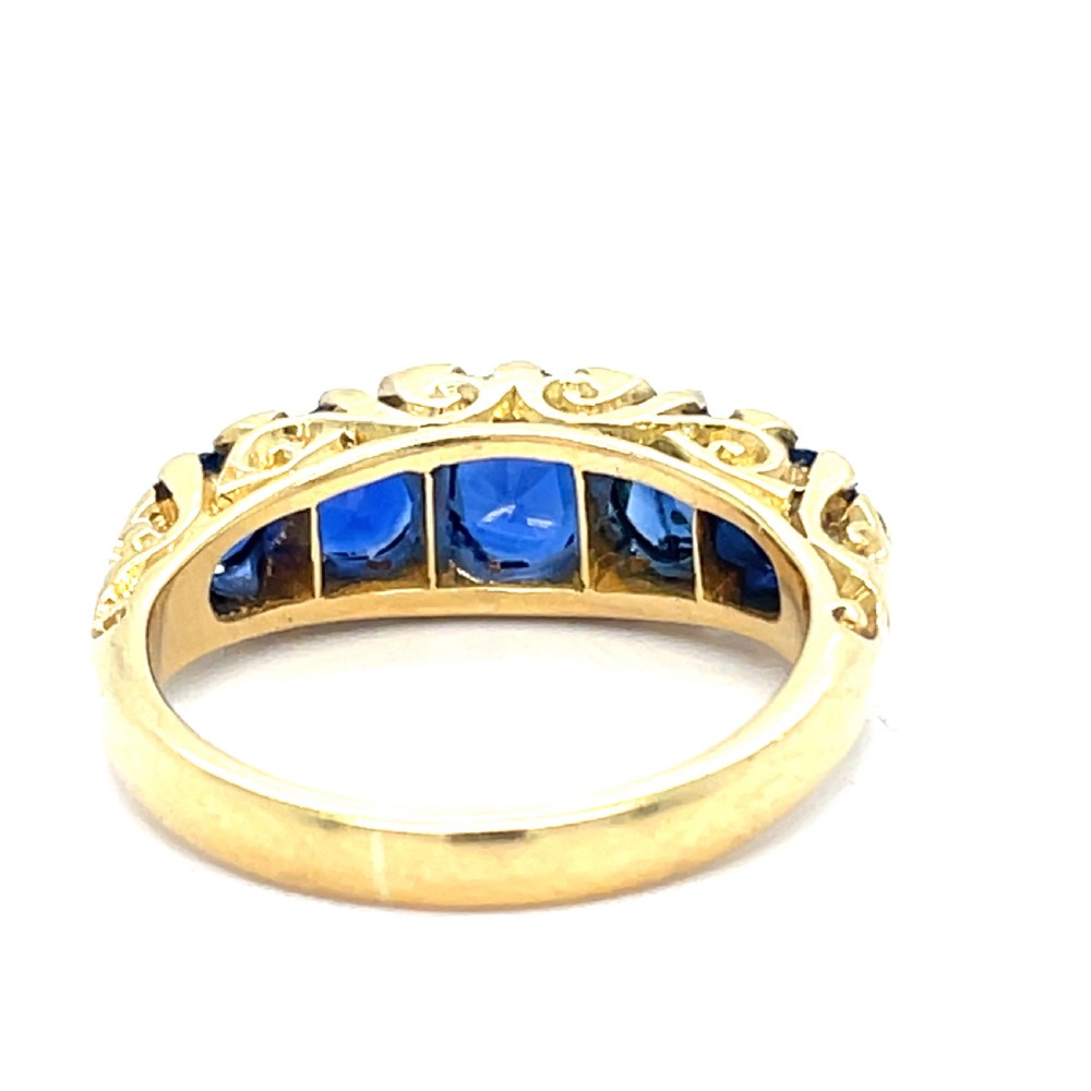A Victorian 18ct yellow gold boat ring set with five graduated oval blue sapphires and small diamond accents. View III