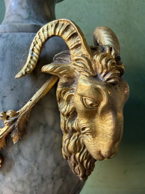 fig 1. A pair of late 19th-century French Louis XVI style Campan vert marble urns adorned with gilt bronze ram head handles, floral swags, and pinecone finials.