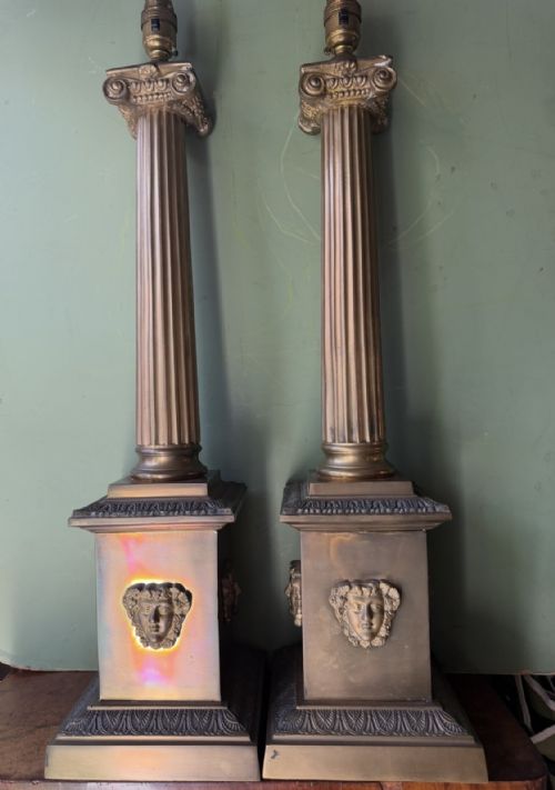 fig 1. A pair of early twentieth-century brass table lamps featuring fluted classical columns, Corinthian capitals, and square pedestal bases decorated with cast face masks.