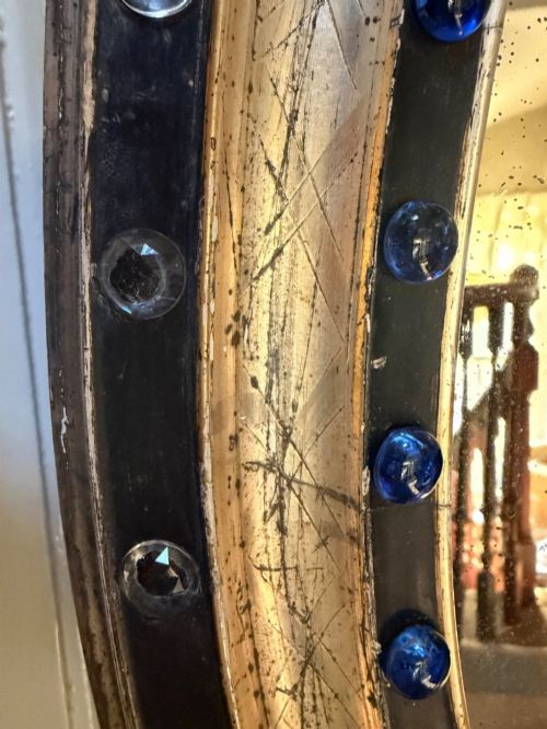 fig 1. A nineteenth-century Irish oval wall mirror featuring an ebonised frame inset with clear facetted glass jewels, an inner silver-gilt band, and cobalt blue glass cabochons.