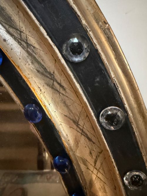 fig 1. A nineteenth-century Irish oval wall mirror featuring an ebonised frame inset with clear facetted glass jewels, an inner silver-gilt band, and cobalt blue glass cabochons.