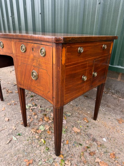 fig 2. A late 18th-century George III mahogany sideboard featuring a serpentine front, stringing inlays, brass octagonal handles, and tapered square legs.