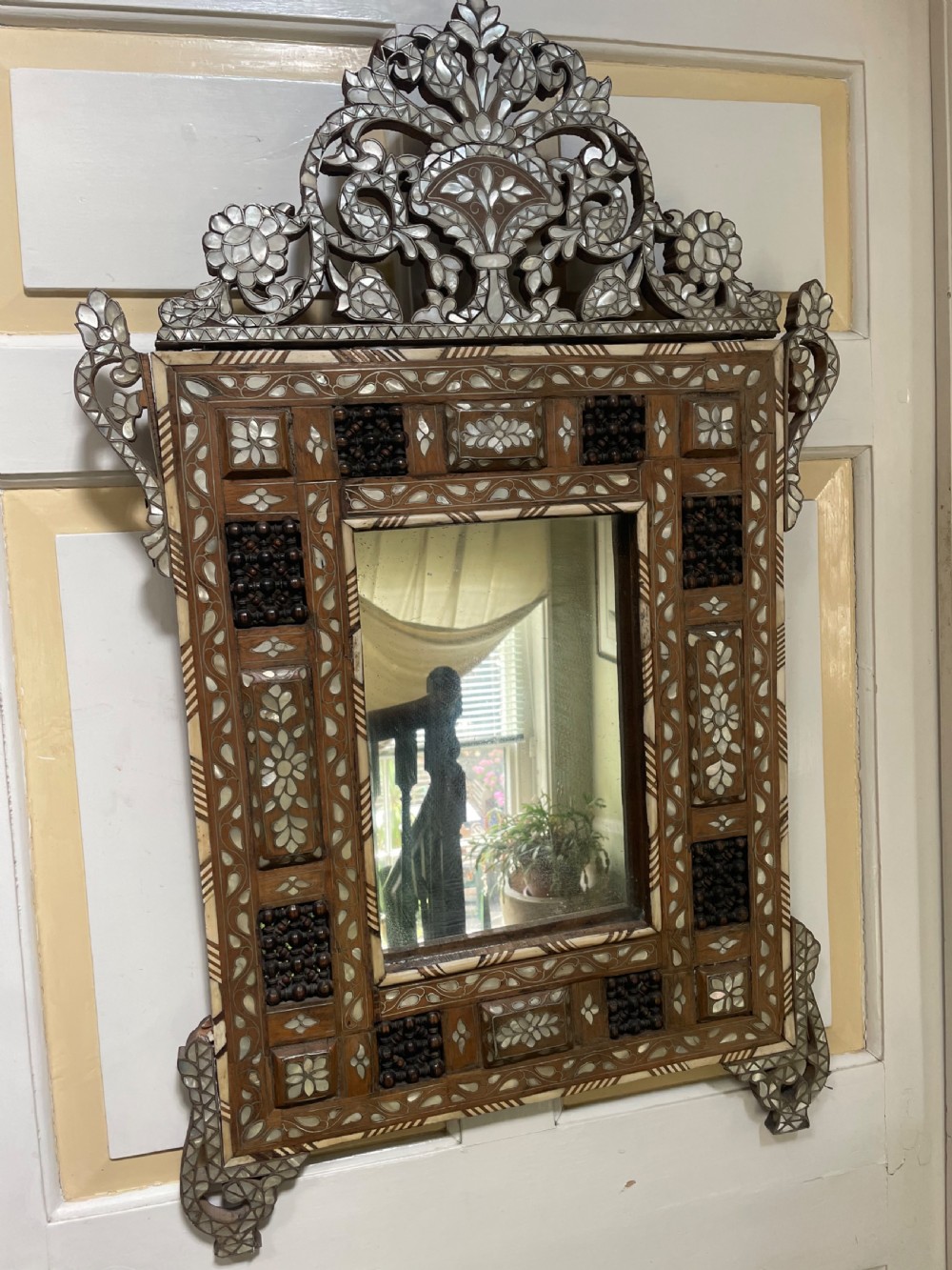 An antique Levantine walnut wall mirror featuring hand-carved decorative cresting and elaborate geometric mother-of-pearl and bone inlay. View II