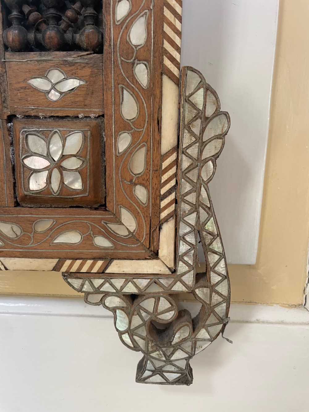 An antique Levantine walnut wall mirror featuring hand-carved decorative cresting and elaborate geometric mother-of-pearl and bone inlay. View IV