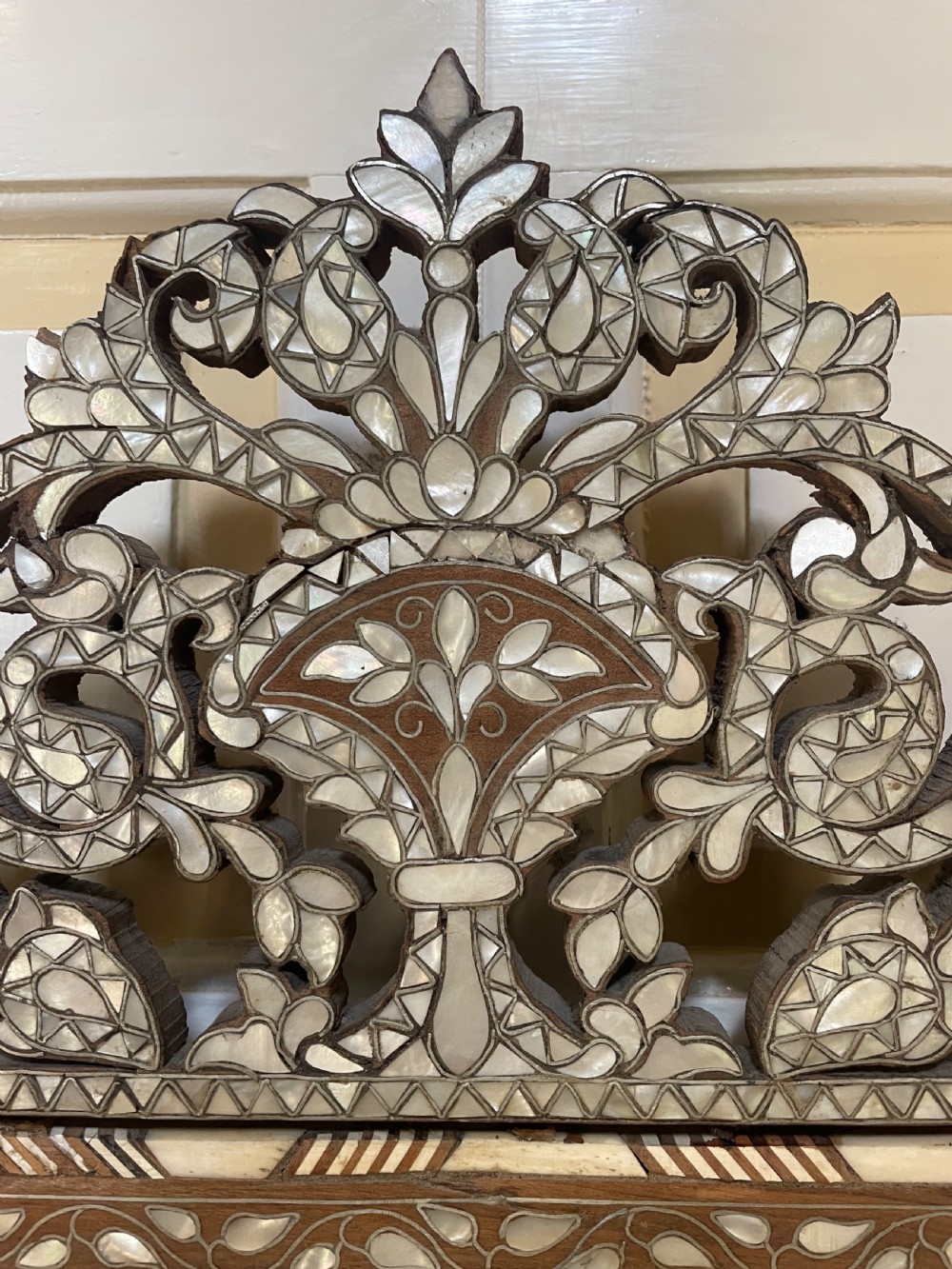 An antique Levantine walnut wall mirror featuring hand-carved decorative cresting and elaborate geometric mother-of-pearl and bone inlay. View V