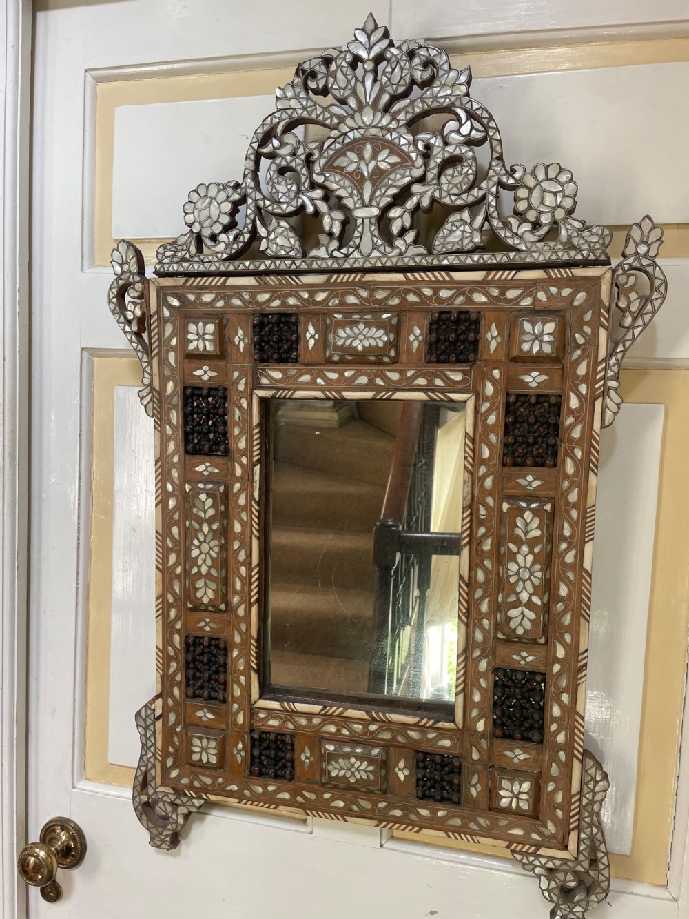 An antique Levantine walnut wall mirror featuring hand-carved decorative cresting and elaborate geometric mother-of-pearl and bone inlay. View VII