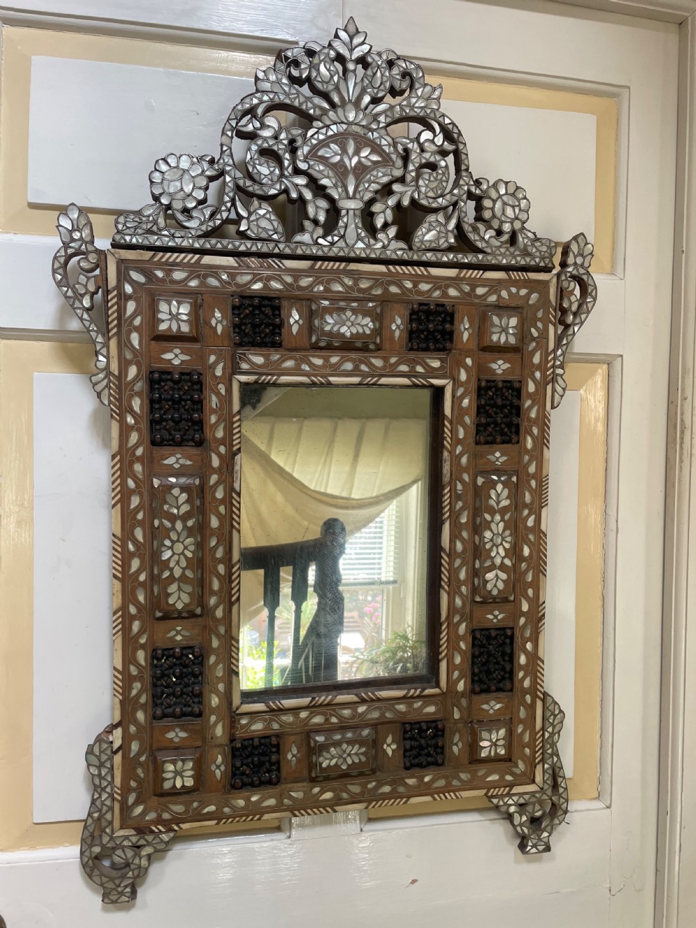 An antique Levantine walnut wall mirror featuring hand-carved decorative cresting and elaborate geometric mother-of-pearl and bone inlay. View VIII