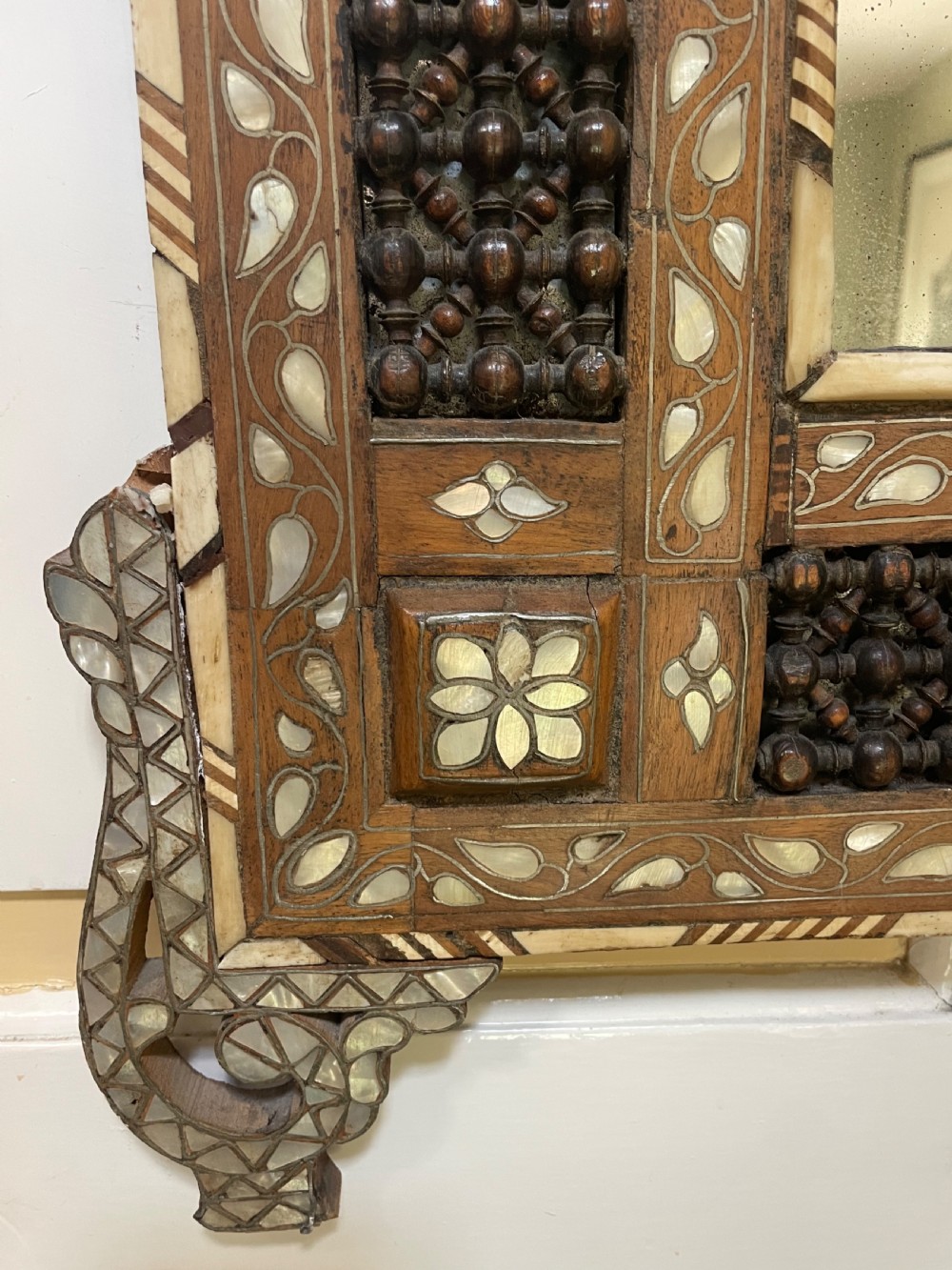 An antique Levantine walnut wall mirror featuring hand-carved decorative cresting and elaborate geometric mother-of-pearl and bone inlay. View IX