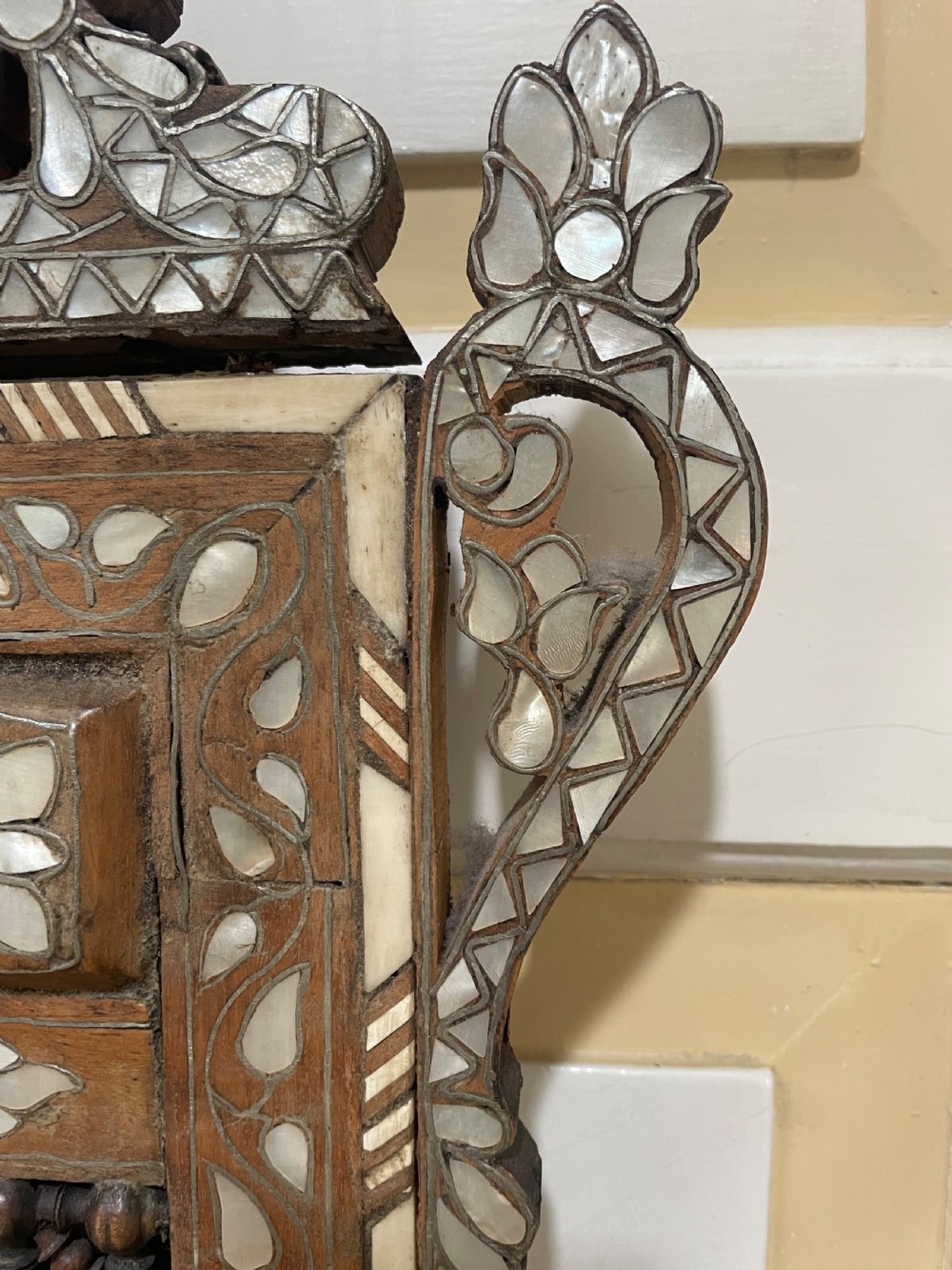 An antique Levantine walnut wall mirror featuring hand-carved decorative cresting and elaborate geometric mother-of-pearl and bone inlay. View XI