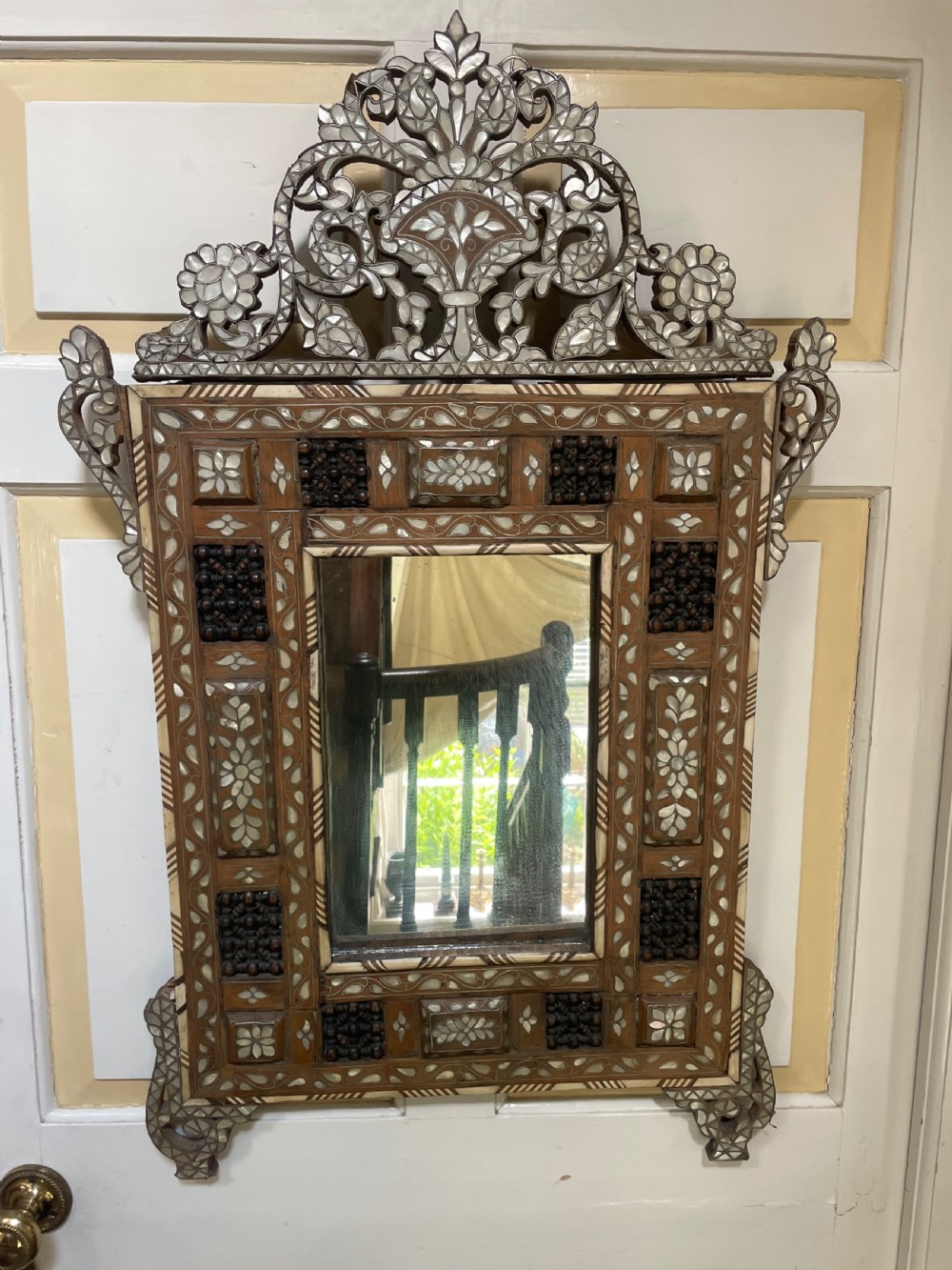 An antique Levantine walnut wall mirror featuring hand-carved decorative cresting and elaborate geometric mother-of-pearl and bone inlay. View XII
