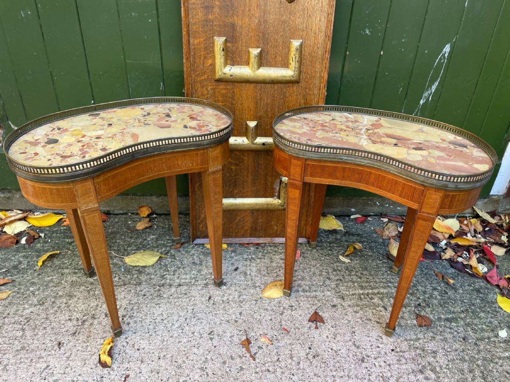 A pair of early twentieth-century French kidney-shaped side tables made from walnut and kingwood with brass galleried marble tops and tapered legs.