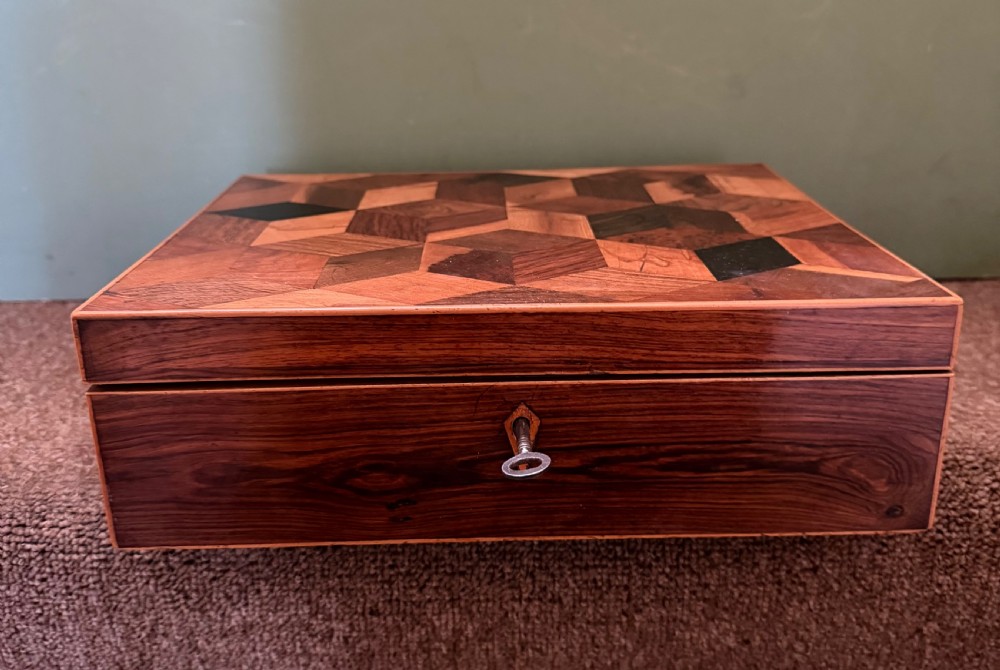 A nineteenth-century rectangular rosewood box featuring a geometric specimen wood parquetry lid and a central keyhole.