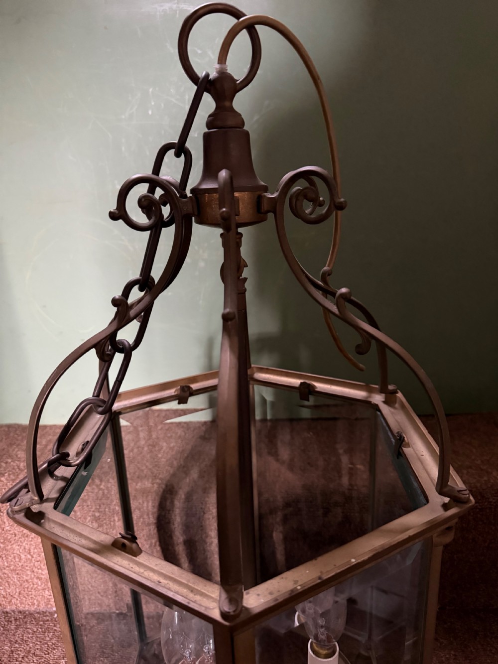 A late nineteenth-century hexagonal brass hanging lantern featuring clear glass panels, scrollwork canopy, and a three-light candle fitting. View V