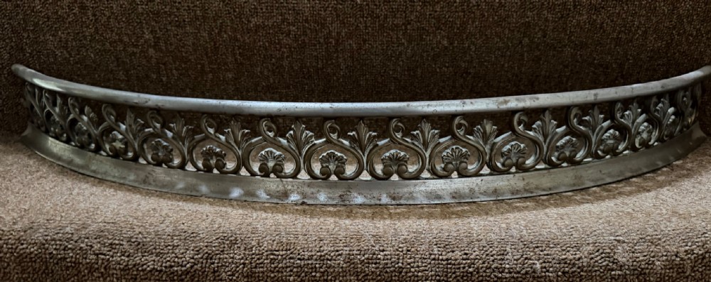 An early 19th-century curved steel fireplace curb featuring openwork Neoclassical cast scrollwork and palmette motifs.