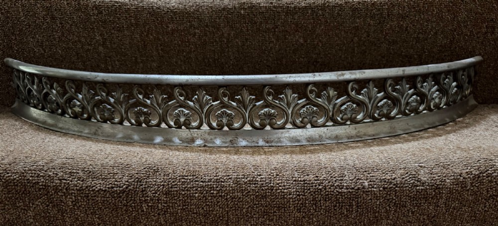 An early 19th-century curved steel fireplace curb featuring openwork Neoclassical cast scrollwork and palmette motifs. View V