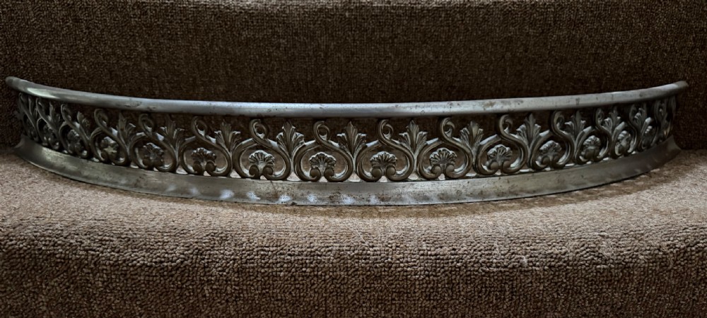 An early 19th-century curved steel fireplace curb featuring openwork Neoclassical cast scrollwork and palmette motifs. View VI