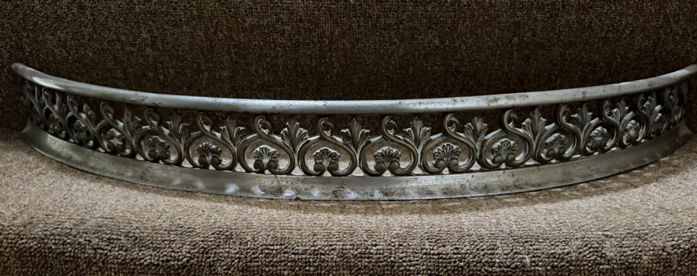An early 19th-century curved steel fireplace curb featuring openwork Neoclassical cast scrollwork and palmette motifs. View IX