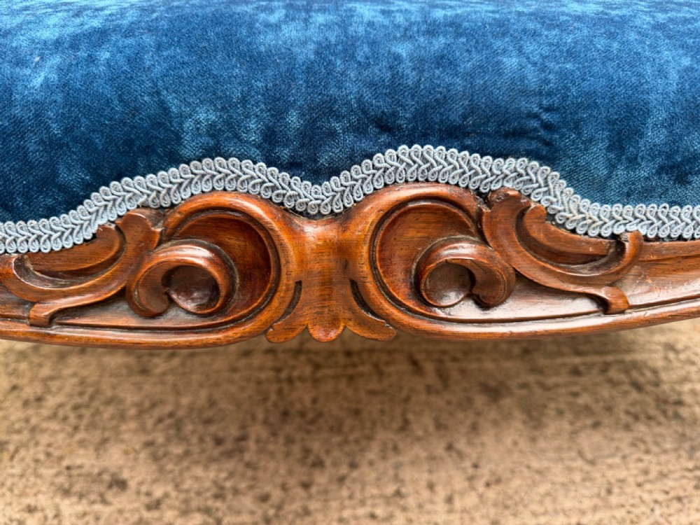 A mid-19th-century centre stool featuring carved walnut cabriole legs, carved aprons, and blue velvet upholstered top. View V