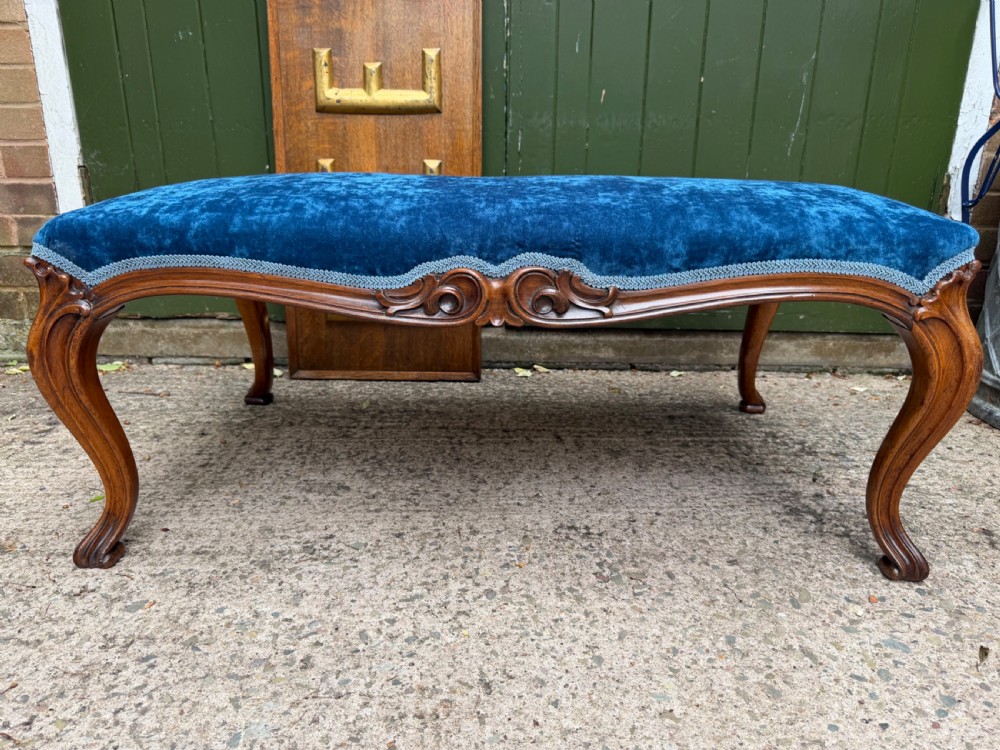 A mid-19th-century centre stool featuring carved walnut cabriole legs, carved aprons, and blue velvet upholstered top. View VI