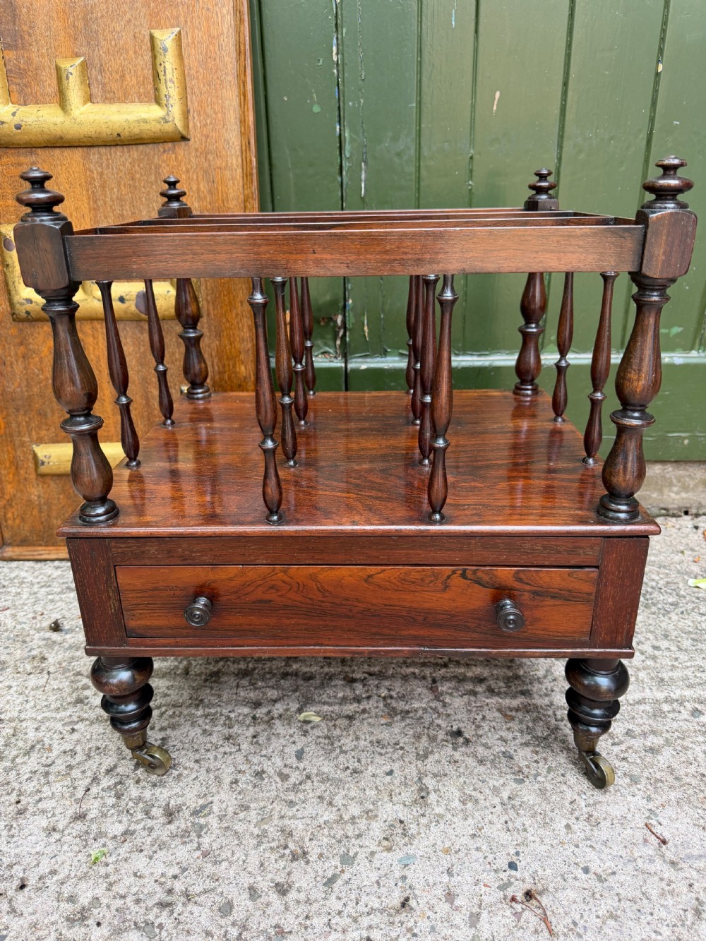 An early nineteenth-century George IV rosewood music canterbury featuring turned spindle divisions, a single base drawer, turned legs, and brass castors. View II