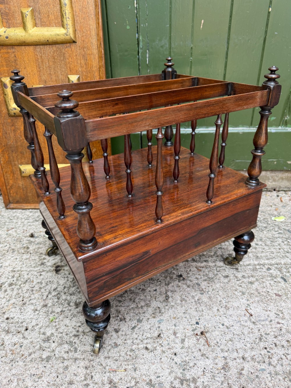 An early nineteenth-century George IV rosewood music canterbury featuring turned spindle divisions, a single base drawer, turned legs, and brass castors. View V