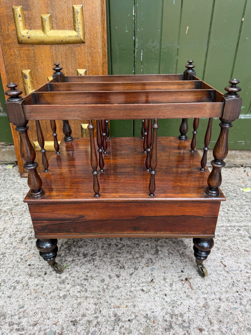 An early nineteenth-century George IV rosewood music canterbury featuring turned spindle divisions, a single base drawer, turned legs, and brass castors. View VI