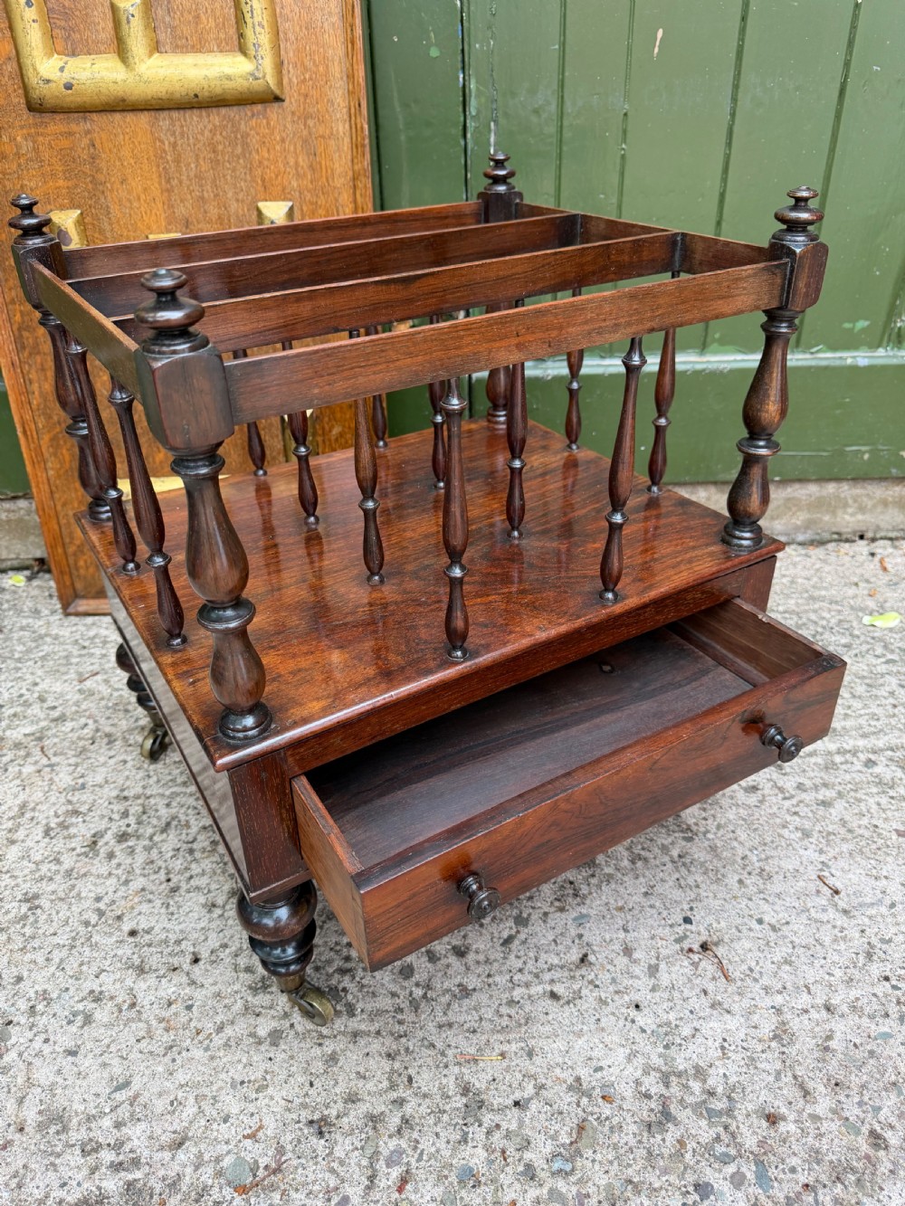 An early nineteenth-century George IV rosewood music canterbury featuring turned spindle divisions, a single base drawer, turned legs, and brass castors. View IX