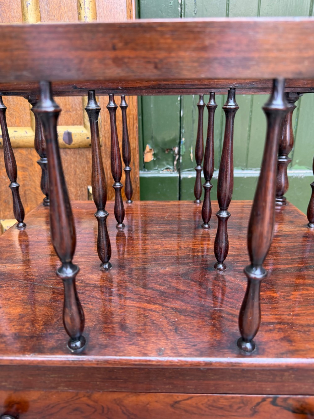 An early nineteenth-century George IV rosewood music canterbury featuring turned spindle divisions, a single base drawer, turned legs, and brass castors. View X