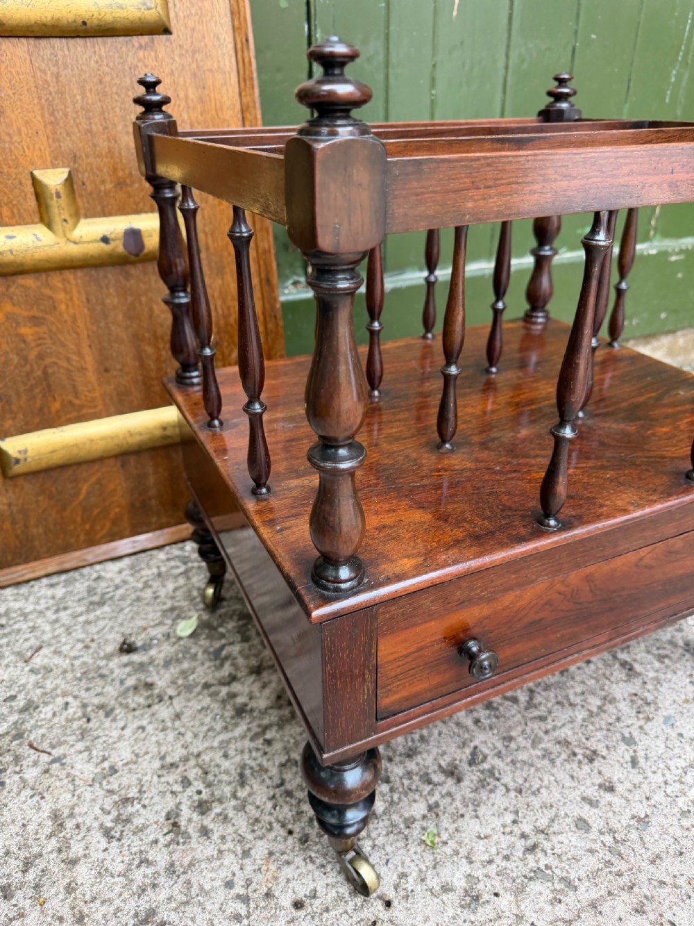 An early nineteenth-century George IV rosewood music canterbury featuring turned spindle divisions, a single base drawer, turned legs, and brass castors. View XI